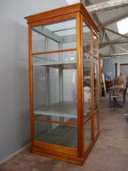 Schräg fotografierte Seitenansicht der vollständig verglasten Lehrmittelvitrine. Die elegante Konstruktion und die großzügigen Glasflächen machen den Schrank ideal für Präsentationszwecke.
