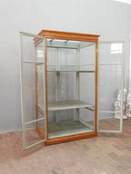 Lehrmittelschrank mit geöffneten Glastüren. Die Aufnahme zeigt den großzügigen Innenraum mit den beiden höhenverstellbaren Einlegeböden und der originalen grau-grünen Innenlackierung.