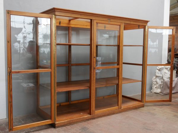 Vorderansicht der seltenen Lehrmittelvitrine der Firma Hermann Fiedler aus Eisleben mit geöffneten Glastüren. Die Aufnahme zeigt den großzügigen Innenraum, die beiden großen höhenverstellbaren Einlegeböden sowie die vollständig verglaste Konstruktion des historischen Schulschranks um 1920.