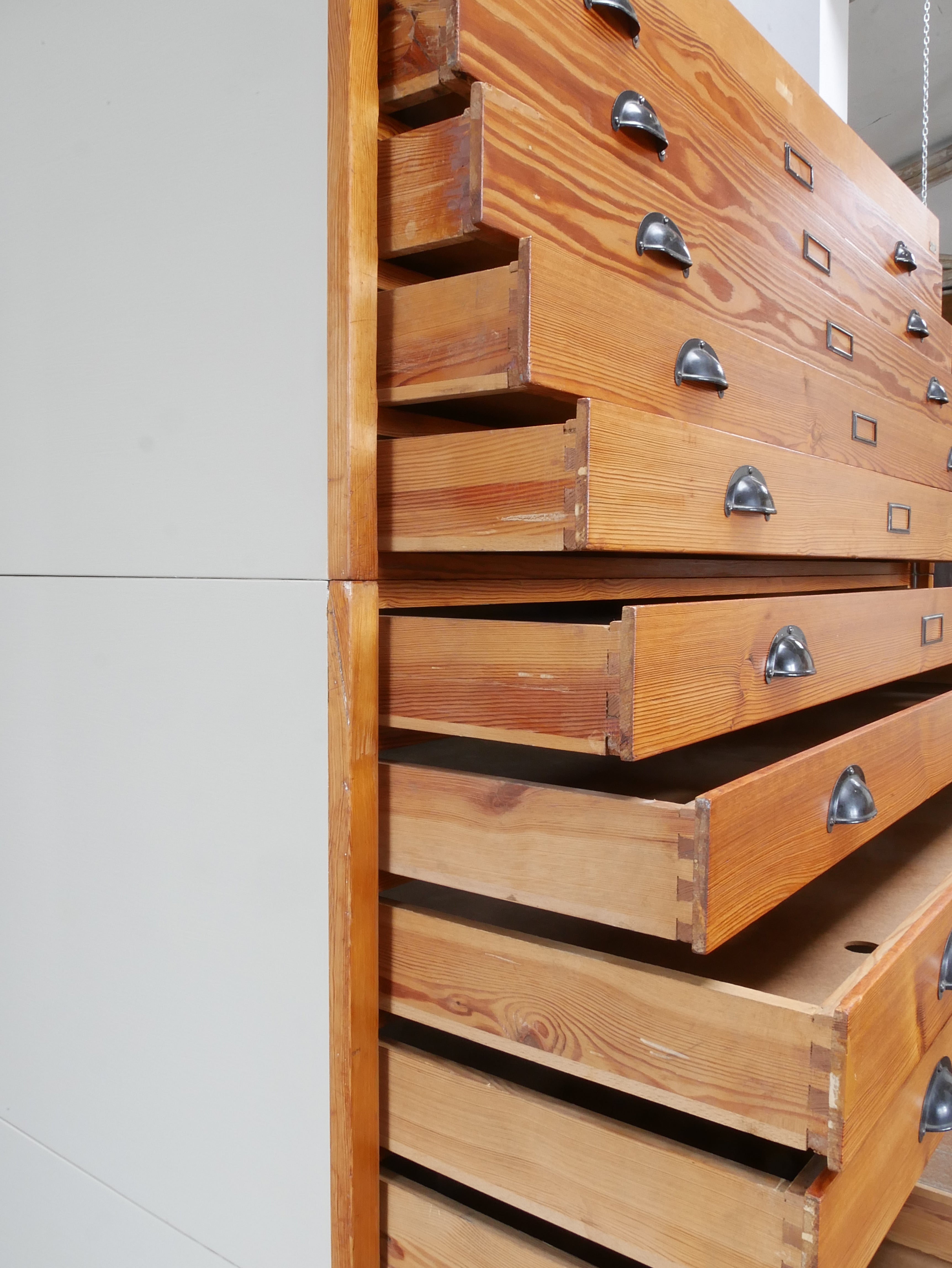 Detailaufnahme der massiven Holzschubladen mit originalen Metallgriffen des REISS Planschranks.