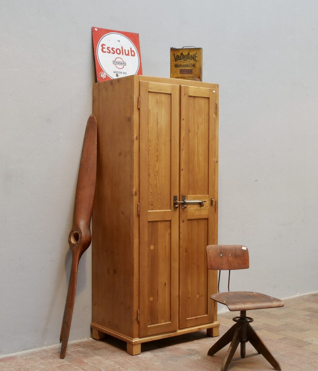 Restaurierter Weichholz-Spind aus der Zeit um 1915 in schräger Vorderansicht. Historischer Militär- oder Industriespind mit originaler Verriegelung, gewachster Oberfläche und massiver Holzkonstruktion.