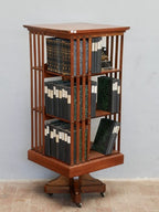 Schräge Seitenansicht des Revolving Bookcase von Hollandia H. Pander & Zonen. Die Aufnahme zeigt die offene Fachaufteilung, die hochwertige Verarbeitung aus massivem Nussbaum sowie die elegante Jugendstil-Konstruktion des drehbaren Bücherregals.
