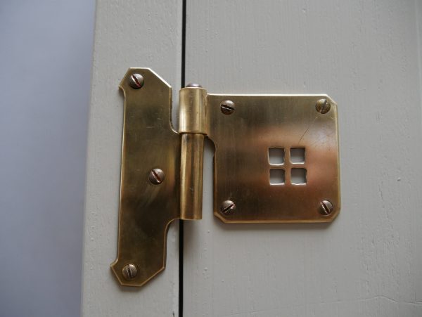 Detailaufnahme eines originalen Messingscharniers. Die hochwertige Ausführung der historischen Beschläge unterstreicht die Qualität des Jugendstil-Möbels.