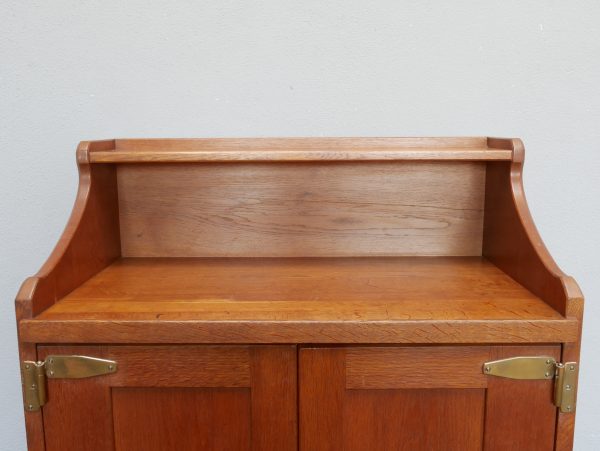 Detailaufnahme des charakteristischen geschwungenen Aufsatzes auf dem oberen Abschluss des Richard-Riemerschmid-Pfeilerschranks. Die elegante Linienführung ist typisch für die Entwürfe der Deutschen Werkstätten Hellerau.