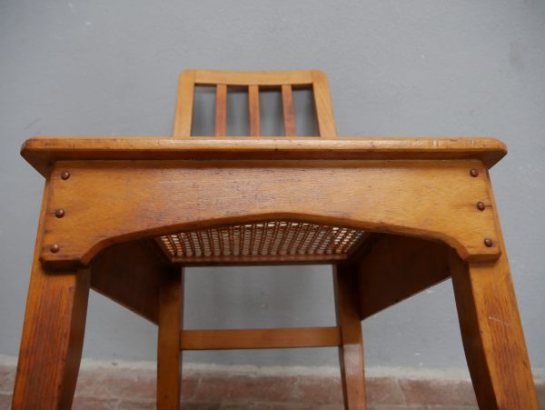 Detailaufnahme der Unterseite eines Richard-Riemerschmid-Stuhls. Sichtbar sind die stabile Zargenkonstruktion, die handwerklichen Holzverbindungen sowie das originale Rohrgeflecht der Sitzfläche.
