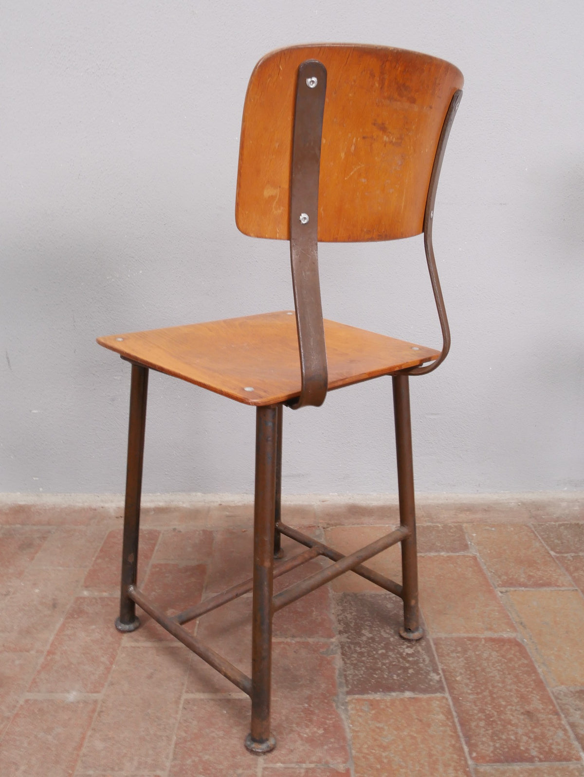 Rückansicht eines einzelnen ROWAC-Hockers. Die charakteristische Holzrückenlehne, das genietete Metallgestell und die stabile Konstruktion dokumentieren die hohe Qualität der originalen Ausführung um 1920.
