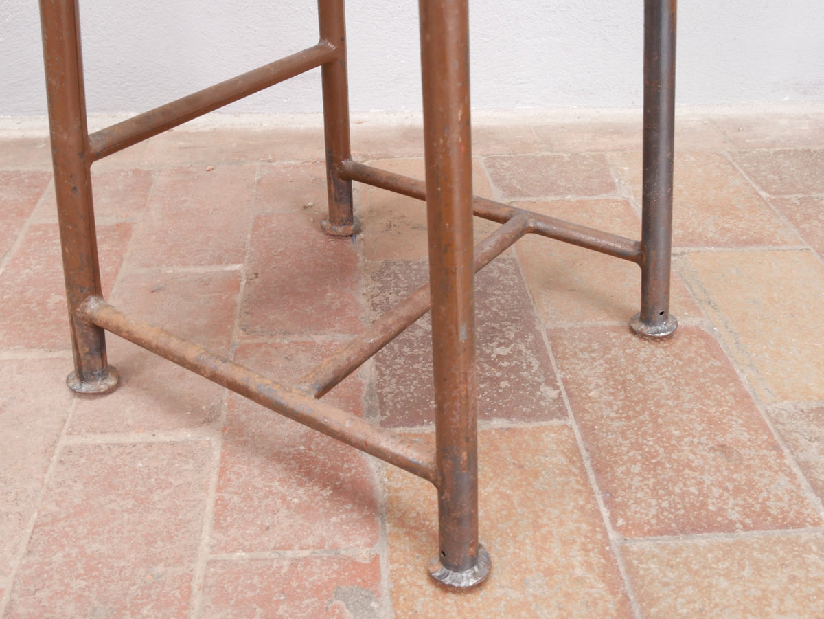 Detailaufnahme des unteren Metallgestells mit den charakteristischen Verstrebungen und Füßen eines originalen ROWAC-Hockers. Die robuste Konstruktion und die altersgerecht erhaltene Oberfläche dokumentieren die hohe Qualität des historischen Industriehockers aus Chemnitz.
