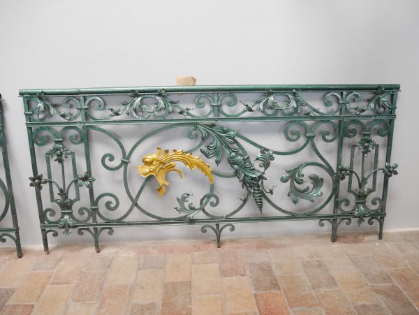 Frontansicht des rechten Geländerelements aus einem ehemaligen Schloss. Die fein geschmiedeten Ornamente, geschwungenen Linien und die vergoldete Schmuckkartusche zeigen die hochwertige Schmiedekunst des Historismus.
