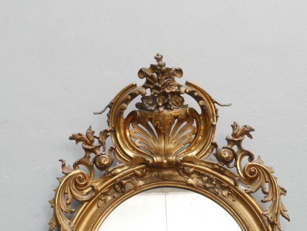 Frontalansicht des oberen Spiegelaufsatzes mit aufwendig gestalteter Krone, vergoldeten Schnitzereien und geschwungenen Ornamenten. Die Aufnahme zeigt die außergewöhnliche Qualität der originalen Stuckvergoldung.