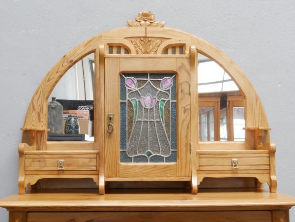 Detailansicht des außergewöhnlich gestalteten Aufsatzes mit originalem Bleiglas, seitlichen Spiegeln, kleinen Schubkästen und kunstvoll geschnitzten Jugendstil-Ornamenten. Die Aufnahme zeigt die aufwendige Gestaltung des oberen Möbelteils.