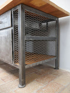 Seitliche Perspektive der restaurierten Werkbank. Sichtbar sind das offene Regal, der Metallrahmen sowie die massive Holzplatte im Industrial-Stil.