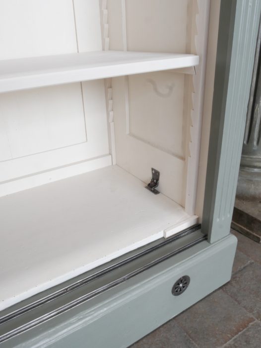 Detailaufnahme des unteren Innenbereichs der restaurierten Bibliotheksvitrine. Sichtbar sind die cremeweißen Einlegeböden sowie die stabile Innenkonstruktion des historischen Schranks.