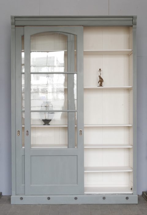 Andere  originale Schiebetür  der historischen Bibliotheksvitrine ist geöffnet und zeigt den großzügigen Innenraum mit höhenverstellbaren Einlegeböden. Die originale Konstruktion und die hochwertige Restaurierung werden deutlich sichtbar.
