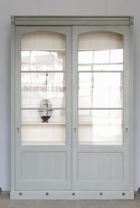 Gerade Frontaufnahme der restaurierten Bibliotheksvitrine mit vollständig geschlossenen Schiebetüren. Das originale Glas und die harmonischen Proportionen des historischen Schranks um 1910 sind hervorragend zu erkennen.