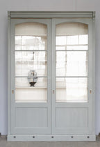 Gerade Frontaufnahme der restaurierten Bibliotheksvitrine mit vollständig geschlossenen Schiebetüren. Das originale Glas und die harmonischen Proportionen des historischen Schranks um 1910 sind hervorragend zu erkennen.