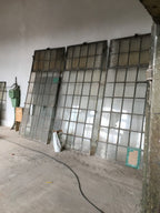 Großes originales XXL-Fabrikfenster aus Schmiedeeisen von etwa 1900 in gutem bis sehr gutem Bergezustand. Die Aufnahme zeigt das historische Industriefenster mit zahlreichen Sprossenfeldern und integriertem Oberlicht, das sich mittels Kette öffnen lässt. Ideal als Restaurierungsobjekt, Loftfenster oder architektonisches Gestaltungselement im Industrie- und Landhausstil.