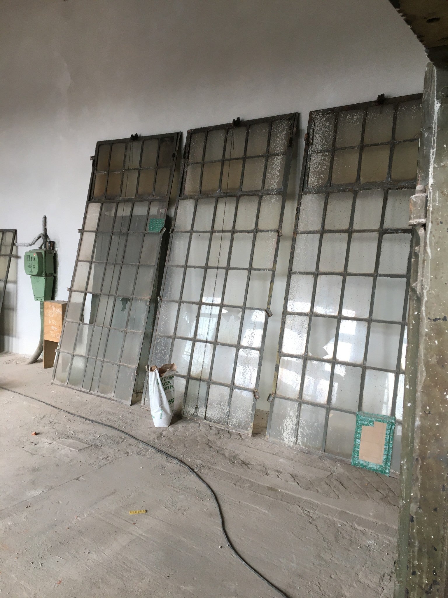 Großes originales XXL-Fabrikfenster aus Schmiedeeisen von etwa 1900 in gutem bis sehr gutem Bergezustand. Die Aufnahme zeigt das historische Industriefenster mit zahlreichen Sprossenfeldern und integriertem Oberlicht, das sich mittels Kette öffnen lässt. Ideal als Restaurierungsobjekt, Loftfenster oder architektonisches Gestaltungselement im Industrie- und Landhausstil.