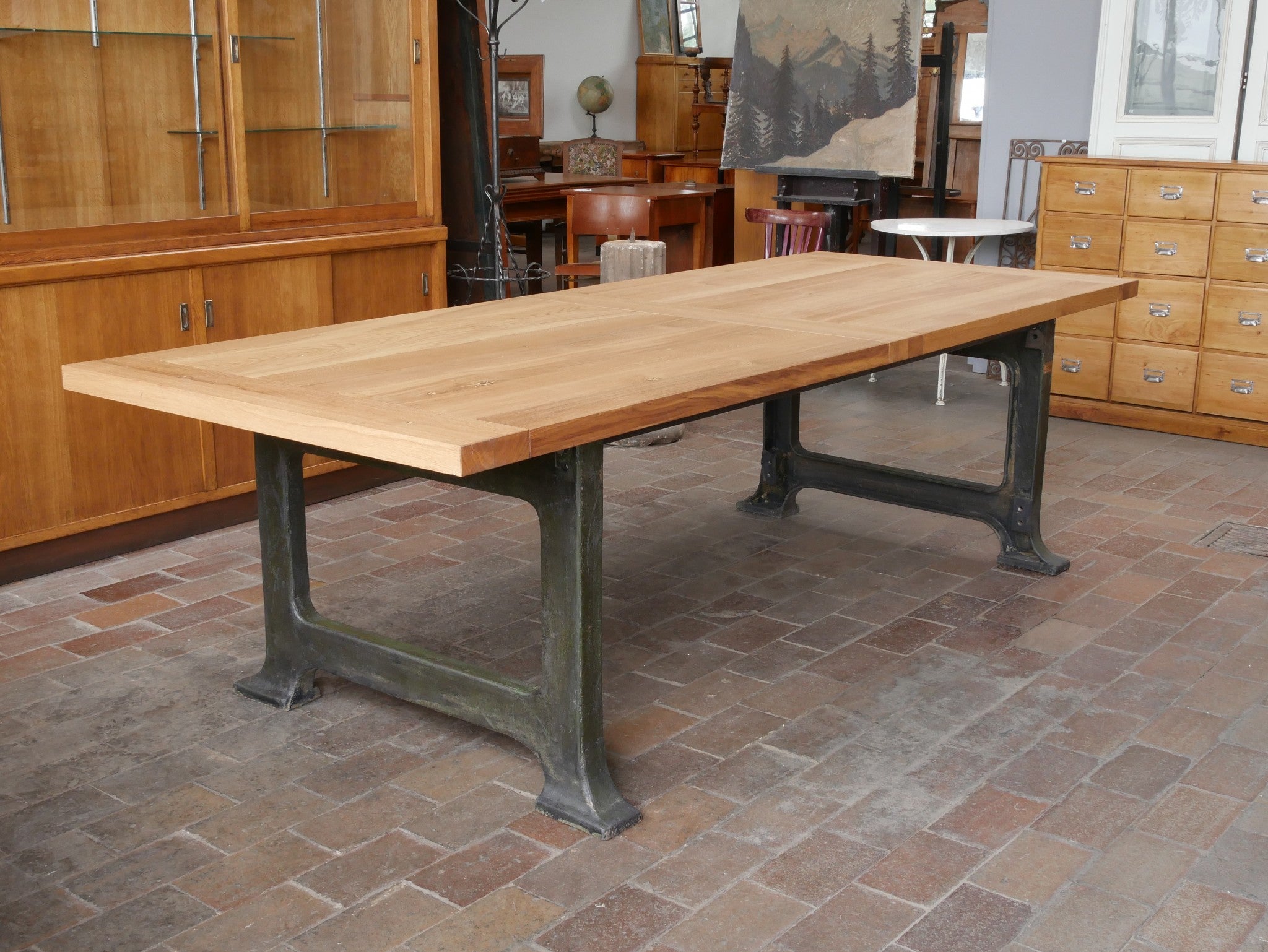 Hauptansicht eines außergewöhnlich großen Konferenz- und Esstisches im Industrielook, original um 1915–1920. Der XL-Tafeltisch besitzt eine zweiteilige, 5 cm starke massive Eichenplatte mit geölter Oberfläche und steht auf schweren Maschinenfüßen aus Gusseisen mit originaler grüner Farbfassung und schöner Alterspatina. Ideal als Konferenztisch, Besprechungstisch oder großer Esstisch.