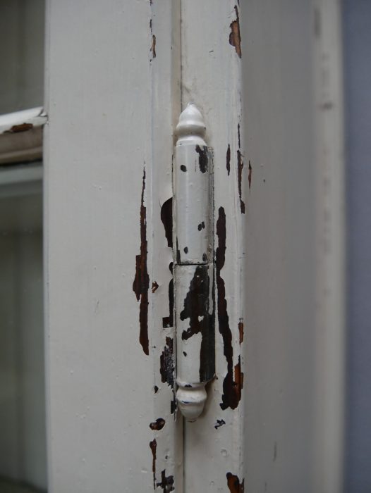 Nahaufnahme des Türrahmens mit erhaltener historischer Farbpatina und sichtbaren altersbedingten Abplatzungen. Die Aufnahme dokumentiert die ursprüngliche Oberfläche und den authentischen, erhaltungswürdigen Zustand des Lehrmittel- und Bibliotheksschranks um 1910.