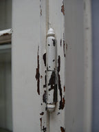 Nahaufnahme des Türrahmens mit erhaltener historischer Farbpatina und sichtbaren altersbedingten Abplatzungen. Die Aufnahme dokumentiert die ursprüngliche Oberfläche und den authentischen, erhaltungswürdigen Zustand des Lehrmittel- und Bibliotheksschranks um 1910.