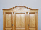 Detailaufnahme der elegant geschwungenen Kranzleiste mit geschnitztem Jugendstilornament. Die hochwertige handwerkliche Verarbeitung des restaurierten Schranks wird hervorgehoben.