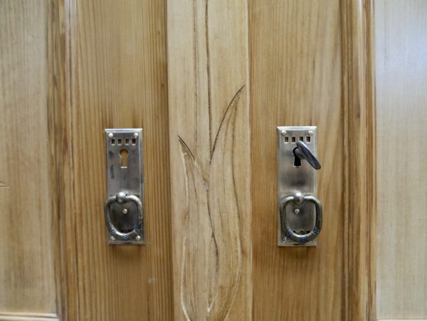 Nahaufnahme der originalen historischen Türbeschläge des Jugendstil-Kleiderschranks. Die authentischen Metallbeschläge unterstreichen den originalen Charakter des Möbelstücks.