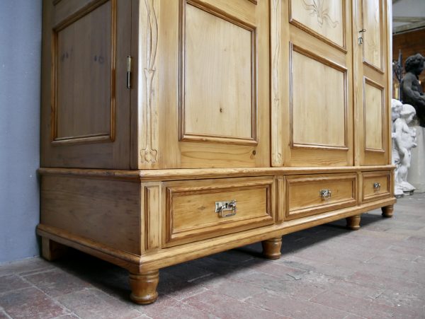 Schräger Blick auf den Sockelbereich mit den drei großen Schubladen, den Seitenfüllungen und dem stabilen Stand des restaurierten Jugendstil-Kleiderschranks.