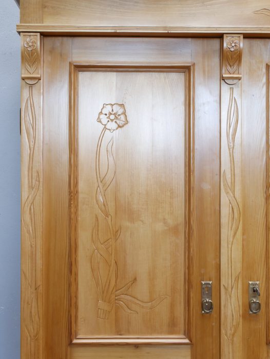 Detailansicht der Schranktür mit aufwendig gearbeiteter Türfüllung, originalem Türbeschlag und typischen Jugendstil-Ornamenten.
