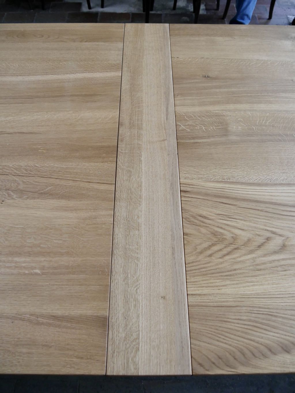 Detailansicht der zweiteiligen Tischplatte aus massiver Eiche. Die sauber gearbeitete Fuge zwischen den beiden Platten zeigt die originale Konstruktion sowie die schöne natürliche Holzmaserung der geölten Oberfläche.
