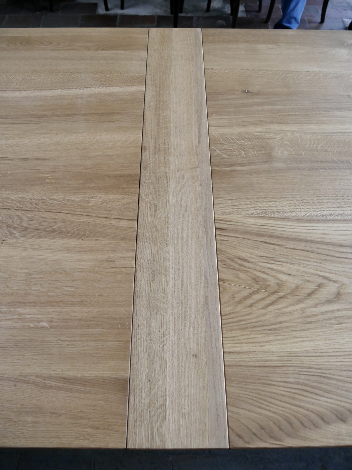 Detailansicht der zweiteiligen Tischplatte aus massiver Eiche. Die sauber gearbeitete Fuge zwischen den beiden Platten zeigt die originale Konstruktion sowie die schöne natürliche Holzmaserung der geölten Oberfläche.
